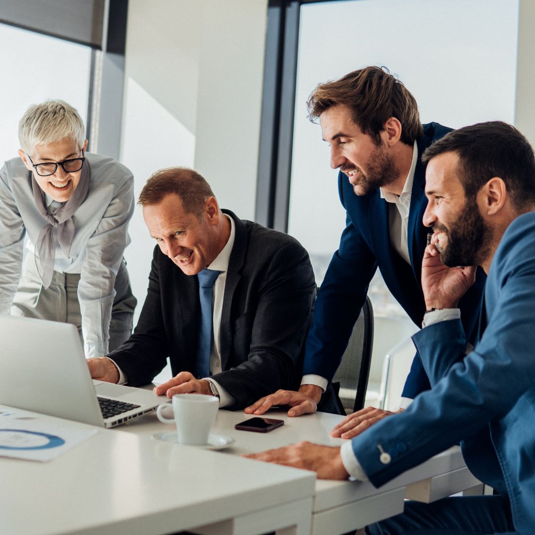 coworkers gathering excitedly around laptop