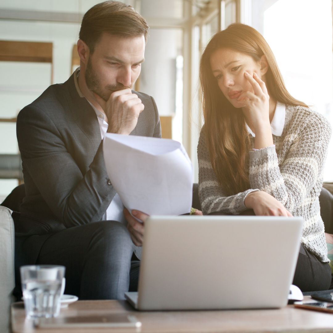 businesspeople looking at paperwork and laptop